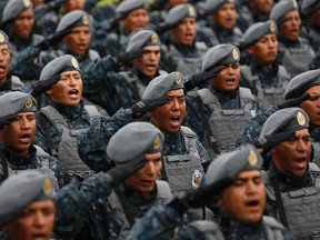 Members of the Gendarmerie Division salute as they sing the national anthem during its presentation at the headquarters of the Federal Police in Mexico City August 22, 2014. Mexico on Friday launched a scaled-back version of a new police force President Enrique Pena Nieto had vowed to create while on the campaign trail to safeguard businesses against rampant organized crime. Pena Nieto originally promised to create a 40,000-member Gendarmerie Division to take the lead in tackling violent crimes such as extortion and kidnapping, given that poorly paid security forces have been easy targets for the cartels to infiltrate and corrupt. REUTERS/Tomas Bravo