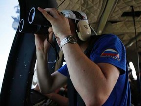 A Russian search team member uses a pair of binoculars to look out the window of a Super Puma helicopter during a search operation for passengers onboard AirAsia Flight QZ8501, off the Java sea, in Indonesia January 7, 2015. REUTERS/Beawiharta