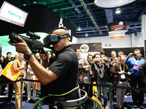A man wearing an Oculus VR headset demonstrates a first person shooter game in a Virtuix Omni virtual reality system at the International Consumer Electronics show (CES) in Las Vegas, Jan. 6, 2015. Wearing special shoes with sensors, the player can actually run in the game.    REUTERS/Rick Wilking