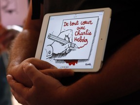 A man holds up a tablet with an image that reads "wholeheartedly with Charlie Hebdo" during a tribute to the victims of a shooting by gunmen at the offices of weekly satirical magazine Charlie Hebdo in Paris, at France's Embassy in Buenos Aires Jan. 7, 2015. Hooded gunmen stormed the Paris offices of the weekly satirical magazine known for lampooning Islam and other religions, shooting dead at least 12 people, including two police officers, in the worst militant attack on French soil in decades.  (REUTERS/Marcos Brindicci)