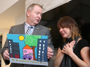 CHEO Foundation president Kevin Keohane presents Lisa Wilton with a painting by a CHEO patient which she can hang in her family's new $1.7 million dream home. DOUG HEMPSTEAD/Ottawa Sun