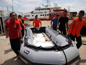 Rescue team members carry an inflatable boat in front of SAR ship KN Purworejo during a search operation for passengers of AirAsia flight QZ8501 at Kumai port in Pangkalan Bun, January 6, 2015.  REUTERS/Beawiharta