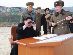 North Korean leader Kim Jong Un looks through a pair of binoculars as he guides the multiple-rocket launching drill of women's sub-units under KPA Unit 851, in this undated photo released by North Korea's Korean Central News Agency (KCNA) in Pyongyang on December 30, 2014. (REUTERS/KCNA)
