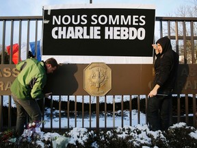 A sign reading "We are all Charlie Hebdo" is erected by embassy personnel at the front gate of the French Embassy in Washington January 7, 2015. Hooded gunmen stormed the Paris offices of a satirical magazine Charlie Hebdo known for lampooning Islam and other religions on Wednesday, killing at least 12 people in the most deadly militant attack on French soil in decades. The French flag flies at half-staff (rear). REUTERS/Gary Cameron