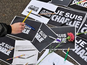 A man puts a pencil on placards reading "I am Charlie" during a minute of silence for the victims of Wednesday's shooting at the Paris offices of weekly newspaper Charlie Hebdo in Ljubljana January 8, 2015.  France began a day of mourning for the 12 journalists and police officers shot dead on Wednesday morning by black-hooded gunmen using Kalashnikov assault rifles.     
REUTERS/Srdjan Zivulovic