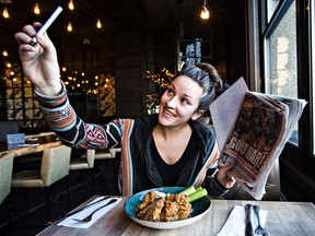 Jessica Starcheski takes a selfie with a plate of wings, a menu and a newspaper at Central Social Hall for the Edmonton Sun's "Put It On Your Plate" contest in Edmonton, Alta., on Thursday, Jan. 8, 2015. Codie McLachlan/Edmonton Sun/QMI Agency