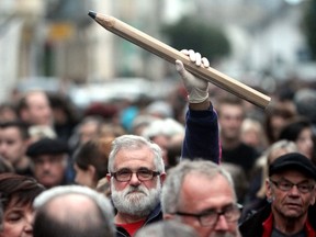 A man holds up a giant pencil during a gathering in Tarbes, southern France, on January 8, 2015, in tribute to the 12 people killed the day before by two gunmen at the editorial office in Paris of French weekly satirical newspaper Charlie Hebdo. AFP PHOTO / LAURENT DARD