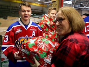 Edmonton Oil Kings assistant captain Edgars Kulda successfully wraps the first present and hands it off to Santas Anonymous executive director, Lana Nordlund on, November 15, 2014. TREVOR ROBB/EDMONTON SUN/QMI AGENCY