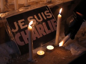A woman places candles next to a placard which reads "I am Charlie" during a gathering in Pristina January 7, 2015, following a shooting by gunmen at the offices of weekly satirical magazine Charlie Hebdo in Paris. Gunmen stormed the Paris offices of the magazine, renowned for lampooning radical Islam, killing at least 12 people, including two police officers in the worst militant attack on French soil in recent decades.  REUTERS/Hazir Reka