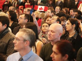 Yusuf Razaghzadeh waves a Maple Leaf flag at a ceremony in Kingston on Friday where his father, mother and sister became Canadian citizens. (Elliot Ferguson/The Whig-Standard)