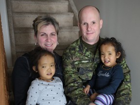 Johanne and Michael Wagner hold their adopted twin daughters Binh, left, and Phuoc, in their Kingston home on Thursday. The twins have a rare genetic disease that will be fatal unless they require liver transplants. The family is trying to raise awareness about live liver donations. (Elliot Ferguson/The Whig-Standard)