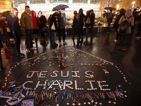People gather near candles with the message, "I am Charlie" as they continue to pay tribute to the shooting victims on Wednesday at the satirical weekly Charlie Hebdo, at the Republique square in Paris January 10, 2015. REUTERS/Pascal Rossignol
