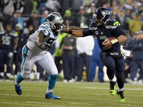 Seattle Seahawks quarterback Russell Wilson (3) runs the ball against the defense of Carolina Panthers defensive end Mario Addison (97) during the second half in the 2014 NFC Divisional playoff football game at CenturyLink Field.  Kirby Lee-USA TODAY Sports