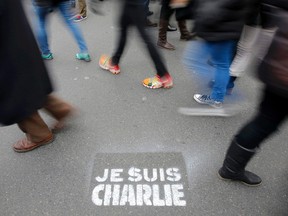People walk past a grafitti tag reading "I am Charlie" as they take part in a solidarity march (Marche Republicaine) in the streets of Paris January 11, 2015. French citizens will be joined by dozens of foreign leaders, among them Arab and Muslim representatives, in a march on Sunday in an unprecedented tribute to this week's victims following the shootings by gunmen at the offices of the satirical weekly newspaper Charlie Hebdo, the killing of a police woman in Montrouge, and the hostage taking at a kosher supermarket at the Porte de Vincennes.    REUTERS/Eric Gaillard