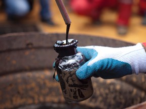 A worker collects crude oil in this July 28, 2011 file photo. REUTERS/Carlos Garcia Rawlins/Files