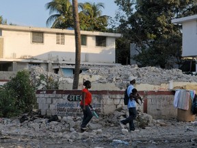 People walk past a house that was destroyed by the January 2010 earthquake in Port au Prince in this January 3, 2012 file photo.  January 12th will mark the fifth anniversary of the devastating earthquake that killed more than 200,000 people.  REUTERS/Swoan Parker/Files