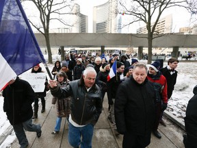 Jean-Pierre Boue holds up the flag of France attached to a hockey stick at a rally held at Nathan Phillips Square to pay tribute to  victims of last week's terrorist attacks. (STAN BEHAL, Toronto Sun)