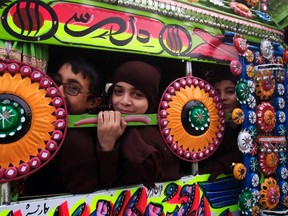 Schoolchildren react inside a decorated van as they head to their school after it reopened in Peshawar on January 12, 2015. (REUTERS/Fayaz Aziz)