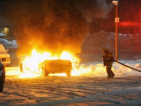 A firefighter attempts to put out a flaming vehicle in Quebec City, Jan. 12, 2015. (NICOLAS BERTHELOT/QMI Agency)