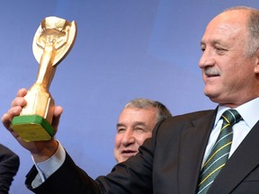 Brazil's national football team coach, Luiz Felipe Scolari, holds a replica of the FIFA World Cup Jules Rimet trophy, during a press conference at a hotel in Rio de Janeiro, Brazil, on May 14, 2013. AFP PHOTO /VANDERLEI ALMEIDA