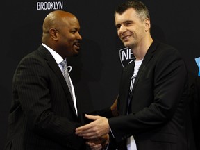 Brooklyn Net's principal owner Mikhail Prokhorov (right), seen here shaking hands with general manager Billy King (left), is exploring the sale of the team, according to a report Tuesday. (Adam Hunger/Reuters/Files)