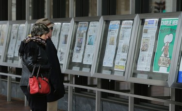 A couple looks at the latest edition of Charlie Hebdo (R) that is seen with U.S. newspapers that are displayed daily at the Newseum in Washington Jan. 14, 2015.   REUTERS/Gary Cameron