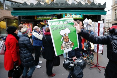 A woman shows a copy of the new issue of satirical French weekly Charlie Hebdo entitled "Tout est pardonne" ("All is forgiven"), which shows a caricature of Prophet Mohammad, in front of a kiosk in Paris, Jan. 14, 2015.  REUTERS/Stephane Mahe