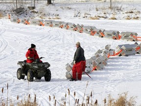 David Smallwood, right and David Dies of Quinte Conservation use an all-terrain vehicle to install 43 new aluminium ice booms the conservation agency has replaced old wooden ones with across the Moira River, along the Lott Dam, in Belleville, Ont. Wednesday, Jan. 14, 2015. - JEROME LESSARD/THE INTELLIGENCER/QMI AGENCY
