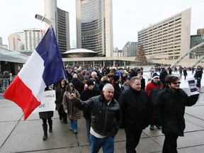Jean-Pierre Boue holds up the flag of France attached to a hockey stick at a demonstration in front of Toronto City Hall on Jan. 11, 2015  following the massacre at the Charlie Hebdo offices in Paris. (Stan Behal/Toronto Sun)
