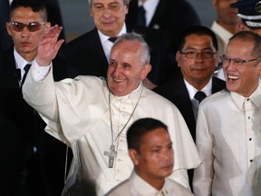 Pope Francis waves to the crowd beside Philippines' President Benigno Aquino, right, upon his arrival at Villamor Air Base for a state and pastoral visit, in Manila on January 15, 2015. (REUTERS/Erik De Castro)