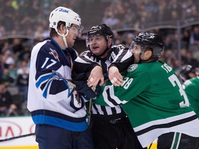 NHL linesman Lonnie Cameron (74) separates Winnipeg Jets left wing Adam Lowry (17) and Dallas Stars centre Vernon Fiddler (38) during the first period at the American Airlines Center Dec. 9, 2014.