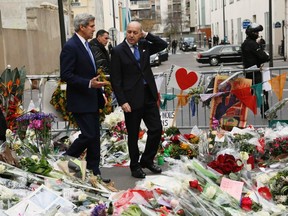 U.S. Secretary of State John Kerry (L) walks with French Foreign Minister Laurent Fabius through a memorial at the site of an attack at the Charlie Hebdo newspaper in Paris Jan. 16, 2015. REUTERS/Rick Wilking