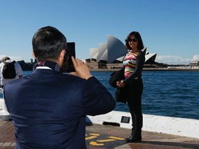 A Chinese tourist poses for a picture in front of the Sydney Opera House in central Sydney June 18, 2013. REUTERS/Daniel Munoz