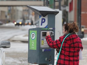 A motorist feeds a parking meter in the SHED district in Winnipeg on Monday. City council approved a proposal to extend the hours for meter parking in the SHED district. (Brian Donogh/Winnipeg Sun)