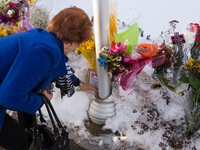 A woman places a plaque on a community memorial for two injured RCMP officers, Aux. Const. Derek Walter Bond and Const. David Matthew Wynn, outside the RCMP detachment at 96 Bellerose Drive in St. Albert, Alta., on Monday, Jan. 19, 2015. (Ian Kucerak/Edmonton Sun)