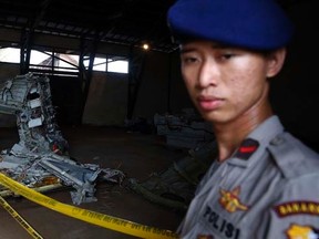 A police officer stands near part of the fuselage of crashed AirAsia Flight QZ8501 inside a storage facility at Kumai port in Pangkalan Bun, January 19, 2015.  REUTERS/Beawiharta