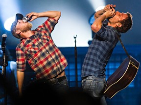 Dierks Bentley, right, shotguns a beer with a fan at Rexall Place in Edmonton in October. Columnist Jordan St. John believes that beer is better when it’s shared. (Codie McLachlan/QMI Agency)