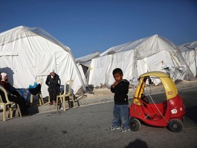 Syrian refugees sit outside the tents in Kokkinotrimithia refugee camp on Jan. 23, 2015. (REUTERS/Yiannis Kourtoglou)