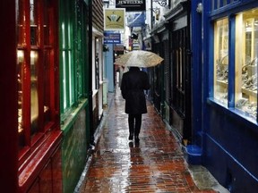 A woman carrying an umbrella walks through The Lanes shopping area in Brighton, southern England, in this January 8, 2015 file photo. Reuters/Luke Macgregor/Files