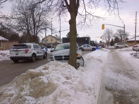 A stolen car is crumpled against a tree, left, and investigators probe a pharmacy robbery, below, all part of a busy Friday morning for London police in the Fanshawe Park Rd. and Adelaide St. N. area. (KATE DUBINSKI, The London Free Press)