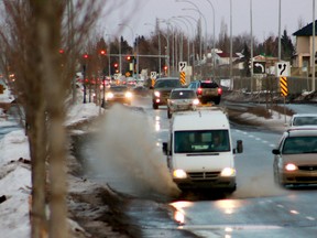 A vehicle drives through a puddle as snow continues melt with above zero temperatures during a warm weather at 167 Ave., and 137 St., on Friday Jan 23, 2015 in Edmonton, Alta.  Hugo Sanchez/Edmonton Sun