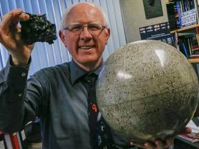 York University Prof. Paul Delaney, pictured in his oiffice on Jan. 23, 2015, holds up a globe of the moon and a chunk of iron meteorite as astroid 2004BL86 will come as close as 1.2 million kilometers on Jan 26, 2015. (Dave Thomas/Toronto Sun)
