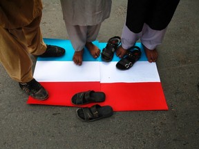 Supporters of religious groups stand on top of a replica of a French flag during a protest against satirical French weekly newspaper Charlie Hebdo, which featured a cartoon of the Prophet Mohammad as the cover of its first edition since an attack by Islamist gunmen, in Lahore January 23, 2015.  REUTERS/Mohsin Raza