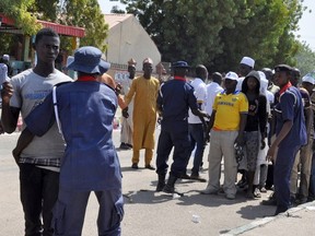 Security officers (blue uniform, red collar) frisk party supporters arriving to attend a rally of the ruling People's Democratic Party (PDP) in Maiduguri on January 24, 2015.  AFP PHOTO/ TUNJI OMIRIN