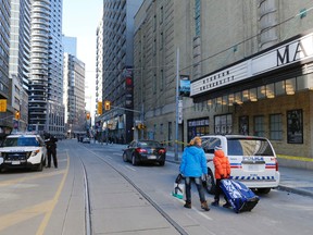 People heading into the former Maple Leaf Gardens for hockey have to navigate around police tape marking one of the two spots on Carlton St. between Yonge and Church where a man attacked four people on Sunday January 25, 2015. (Michael Peake/Toronto Sun)