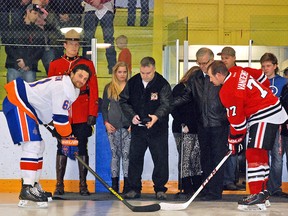 Stacy Lievaart, centre, who is facing a long road to recovery following a tragic motorcycle crash last summer that claimed the life of his close friend Phil Clement, does a ceremonial puck drop Friday night at the Vulcan District Arena ahead of a benefit hockey game supporting the affected families. Two teams from the Chinook Hockey League — the Okotoks Drillers and the Innisfail Eagles — played a regular season game. Simon Ducatel Vulcan Advocate