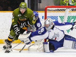 Sudbury Wolves goalie Troy Timpano (33) slides over to the post and defenceman Jeff Corbett (5) gets his stick in the way as North Bay Battalion overage forward Ray Huether (10), a former Wolves player, attempts a wraparound during second-period OHL action at Memorial Gardens in North Bay on Sunday. Timpano saw 38 shots in the game as North Bay skated to a 6-0 win.