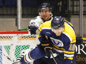 Laurentian Voyageurs forward Dan Pachis (16) takes a cross check in the back from Nipissing Lakers defenceman Mitch McNeill (42) as a shot comes in from the point, hitting the Lakers player in the leg, during OUA hockey action at Memorial Gardens, Friday. The Lakers won 4-1 to grab a slim lead over Laurentian for fourth place in OUA East Division standings.
