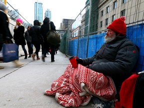 Daniel looks for change along Bay St. on Sunday. (DAVE ABEL, Toronto Sun)