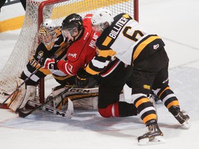 Owen Sound Attack's Daniel Milne, centre, tries to get his stick onto a loose puck beside the net as Kingston Frontenacs defenceman Nathan Billitier checks him into Frontenacs' goalie Lucas Peressini during the first period of Ontario Hockey League action at the Harry Lumley Bayshore Community Centre in Owen Sound on Saturday. (James Masters/QMI Agency)